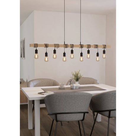 Hosmane 9 Light Linear Pendant Light featuring a pale wood beam with black cords and lampholders, shown suspended above a dining table in a neutral-toned room.