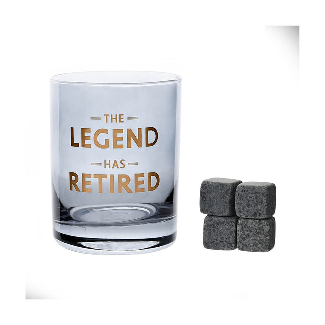 Round glass whiskey tumbler with blue tint and gold "THE LEGEND HAS RETIRED" text, straight sides, thick base, shown with four grey whiskey stones on a white background.