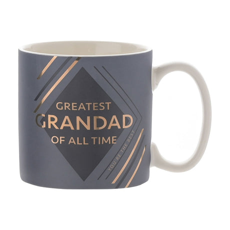 Blue matt mug with white interior and handle, featuring "Greatest Grandad of All Time" in gold text within a charcoal diamond and diagonal gold line accents, on a plain white background.