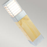 Transform your outdoor space with the Halmstad Medium Bollard in Natural Wood and Silver. This wall-mounted light features a sleek design with horizontal slats covering the light source, offering a contemporary aesthetic. Its blend of natural wood finish and metal accents makes it an elegant addition against any plain, neutral backdrop.