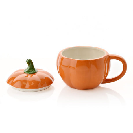Orange pumpkin-shaped stoneware mug with lid, ribbed glossy body, cream interior, and curling green stem handle on lid, shown separately on a white background.