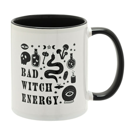 White stoneware mug with black interior and handle, featuring Bad Witch Energy text and witchy motifs like a skull, snake, potion bottles, crystal ball and stars.