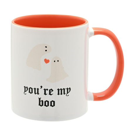 White stoneware mug with orange interior and handle, printed with two ghosts, a heart, and "you're my boo" in black gothic script, on a plain white background.