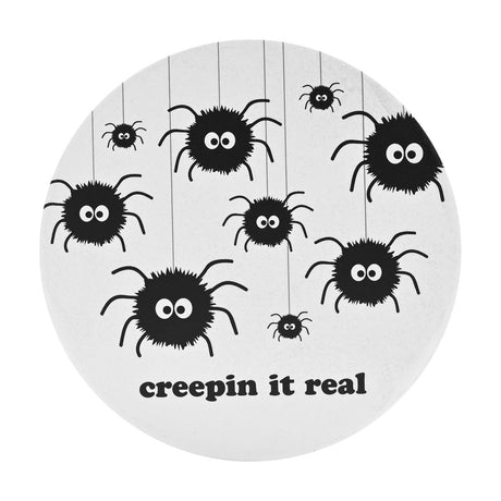 Round white ceramic coaster featuring fuzzy black spiders with wide eyes dangling on threads, with "creepin it real" printed in bold black lowercase text.