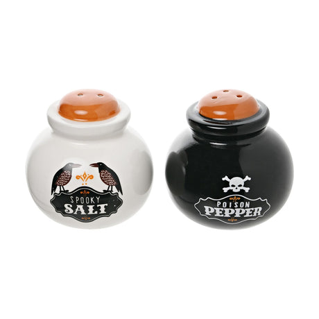 Stoneware salt and pepper shaker set shaped like cauldrons with orange lids, one white with crows labeled Spooky Salt, the other black with a skull labeled Poison Pepper.