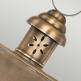 A close-up of the Hyde 1 Light Outdoor Wall Light in aged brass highlights its vintage appeal. This wall light features a vented top with a circular pattern of cutouts for ventilation and a loop handle at the top, while its antique finish adds to its timeless charm.