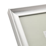 Close-up of a rectangular photo frame's mitred corner in brushed silver finish, showing sloped moulding with visible grain lines, on a plain white background.