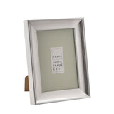 Traditional rectangular easel photo frame in brushed silver finish with sloped moulding, 5 x 7" size, shown at an angle with back stand, on a plain white background.