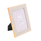 Rectangular photo frame with a textured white border and thin gold edge, shown at an angle with back stand, holding a 5x7 sample insert on a white background.