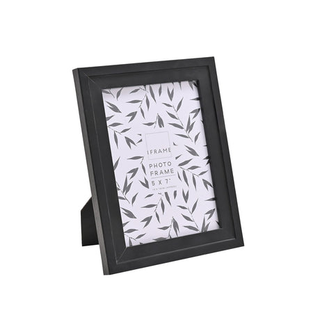 Black wooden photo frame with curved inner edge and easel back, 5x7" size, shown at an angle on a plain white background with sample leaf print insert.