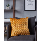 Iles Cushion in ochre yellow with a diagonal basketweave front panel, shown on a dark grey armchair in a living room setting.