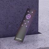 The Exility Smart Lighting Remote Control - Black, branded with MAYTONI, leans against a speckled stone surface. It features buttons for power, color, brightness, and navigation in a circular layout. Sync it with the Maytoni Smart app to enhance functionality.