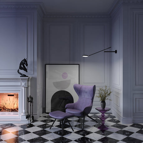 A cozy room showcases a purple lounge chair with a matching ottoman on a black and white checkered floor. A framed abstract print leans against the wall as the Fad Dimmable LED Adjustable Long Wall Light - Black illuminates the softly lit fireplace.