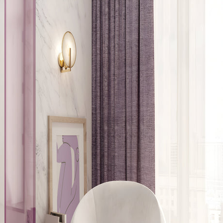 A modern interior showcases a marble wall with a Marmo Wall Light - Gold & Round Natural Stone, softly illuminating the abstract art. Nearby, a white chair complements purple curtains alongside sheer white drapes, enhancing the elegance of the stone backdrop.