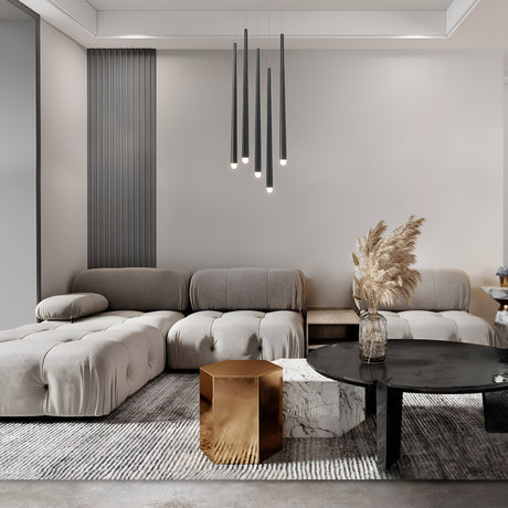 A modern beige sectional sofa, black circular coffee table, and geometric gold marble side table enhance the stylish living room. The Cascade CCT Dimmable LED Cluster Pendant Light in black illuminates the space, while pampas grass adds natural elegance to the minimalist decor and neutral tones.