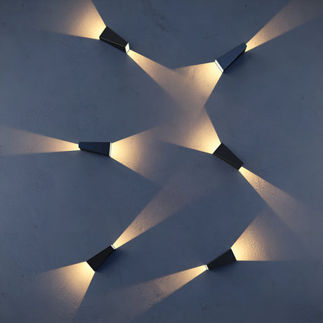 Six Times Square Outdoor Wall Lights, crafted with corrosion-resistant aluminium in black, project intersecting beams of warm 3200K light on a dark gray wall, casting dynamic shadows and adding a modern artistic touch to the minimalist setting.