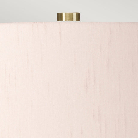 Close-up of the upper section of a cylindrical beige lampshade with a smooth texture. A small, metallic, cylindrical finial is prominently visible at the top against a light gray background, seamlessly enhancing the elegance of the Isla 1 Light Table Light - White/Light Pink ceramic base lamp.
