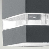 Close-up of the Jannik 1 Light Outdoor LED Wall Light, featuring a sleek graphite rectangular body and a transparent strip for illumination. Its energy-efficient lighting creates a striking effect against the light gray background, highlighting its design and durability with an IP44 rating.