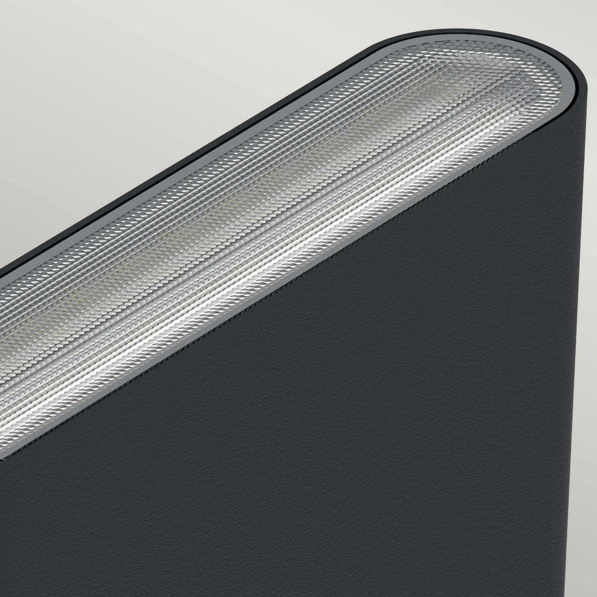 A close-up view of a dark gray fabric surface with an angled, textured edge reveals a modern and sleek design, similar to the finish of die-cast aluminum. The lighting accentuates the material's intricate details against a light gray background, reflecting the durability and style of the Jens-2 LED Outdoor Wall Light - Black.