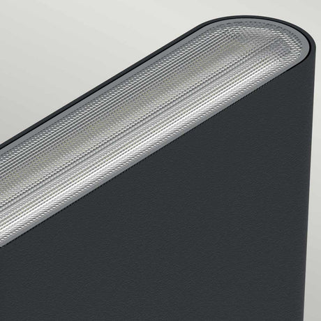A close-up view of a dark gray fabric surface with an angled, textured edge reveals a modern and sleek design, similar to the finish of die-cast aluminum. The lighting accentuates the material's intricate details against a light gray background, reflecting the durability and style of the Jens-2 LED Outdoor Wall Light - Black.