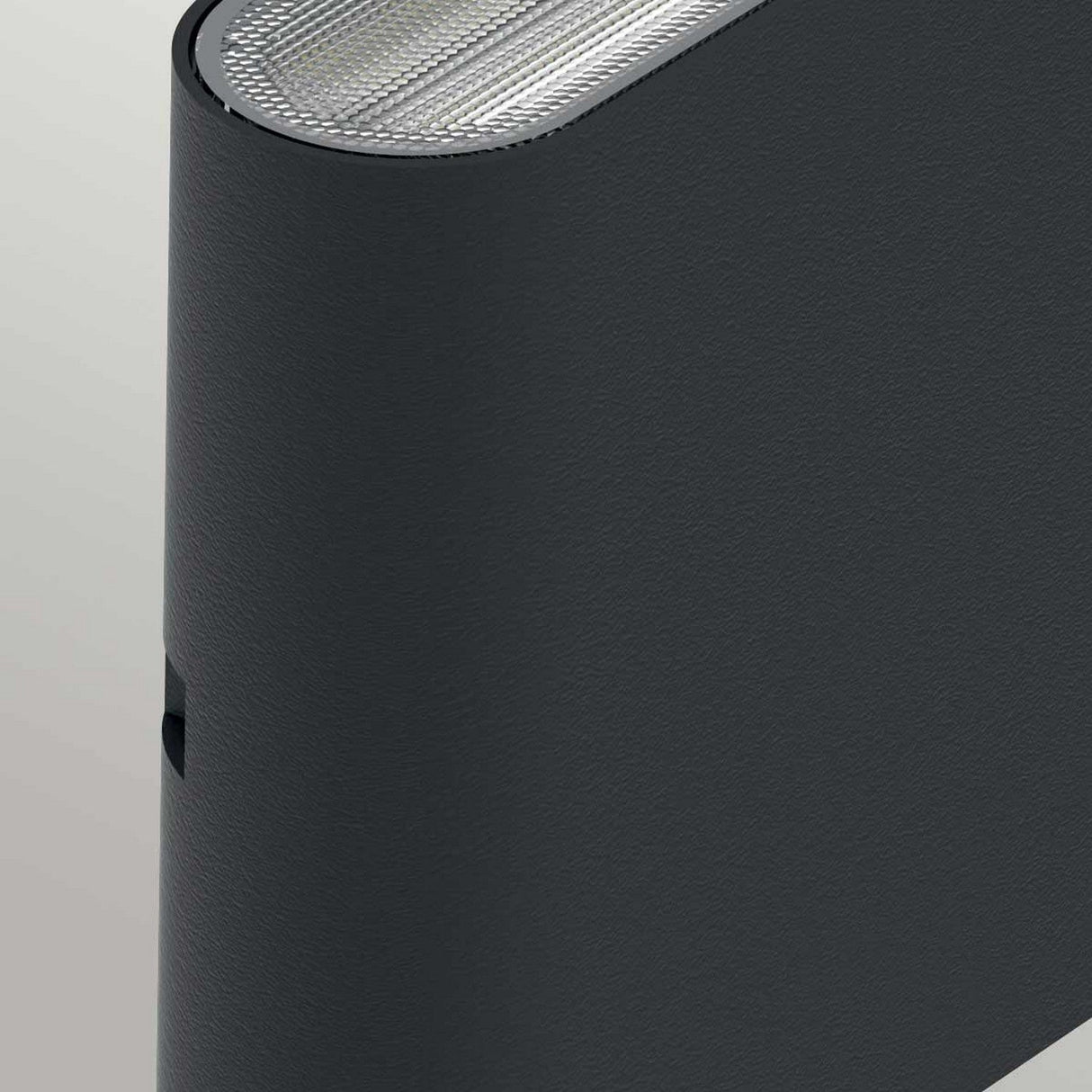 Close-up of a sleek Jens-2 LED Outdoor Wall Light in black, boasting a curved design crafted from die-cast aluminum for durability. The textured top surface suggests ventilation or speaker grilles, while its IP65 rating and minimalist style convey a modern aesthetic perfect for outdoor settings.