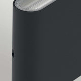 Close-up of a sleek Jens-2 LED Outdoor Wall Light in black, boasting a curved design crafted from die-cast aluminum for durability. The textured top surface suggests ventilation or speaker grilles, while its IP65 rating and minimalist style convey a modern aesthetic perfect for outdoor settings.
