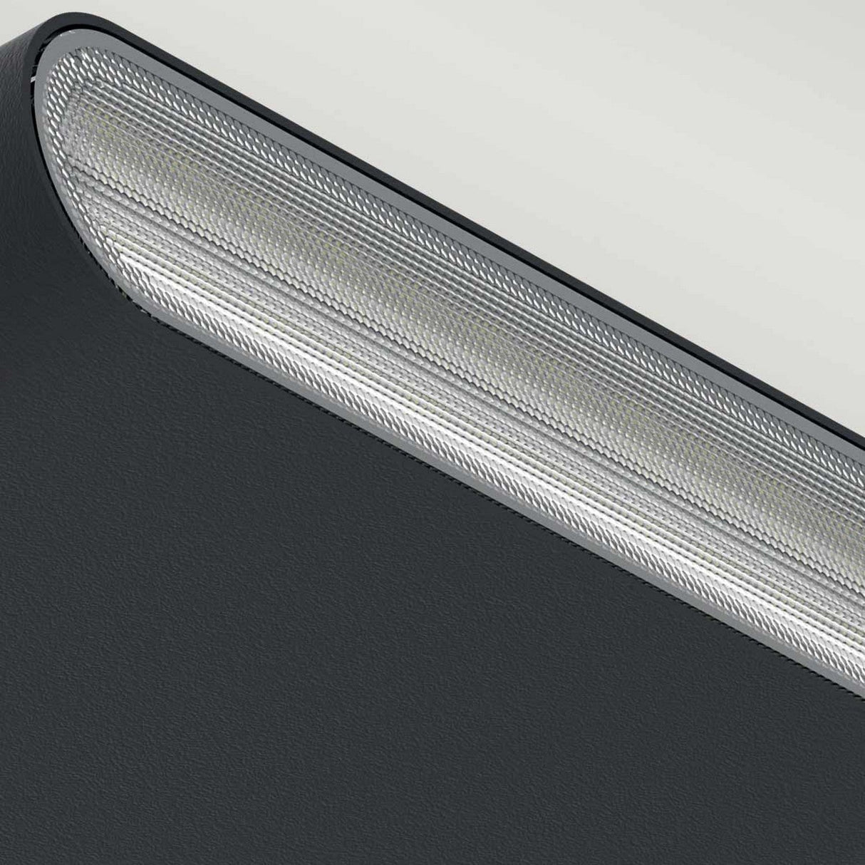 Close-up view of the Jens-2 LED Outdoor Wall Light in black, showcasing its sleek and modern design with a textured fabric-like exterior and a metallic mesh grille on top. It's crafted from die-cast aluminium for durability, set against a light background.