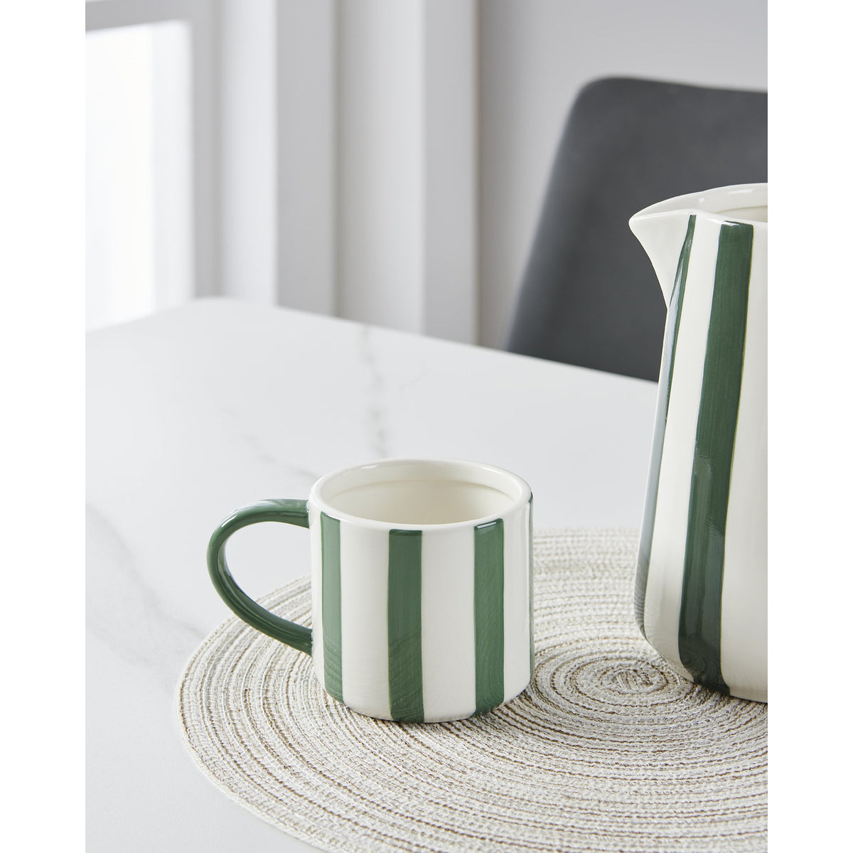 Jinjiti Mug in white ceramic with bold green vertical stripes and a green handle, shown beside a matching striped jug on a marble table.
