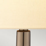 Close-up of the Job 1 Light Table Lamp, showcasing its cream faux silk shade set upon a glossy bronze metallic base. The light gray background highlights the lamp’s sleek and minimalist design.