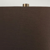 Close-up of the Job 1 Light Table Lamp, featuring a dark brown faux silk lampshade with a matte texture. A small cylindrical metallic finial is visible at the top, accentuating the bronze metallic design of the lamp against a neutral background.