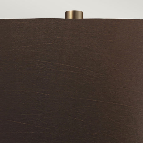 Close-up of the Job 1 Light Table Lamp, featuring a dark brown faux silk lampshade with a matte texture. A small cylindrical metallic finial is visible at the top, accentuating the bronze metallic design of the lamp against a neutral background.