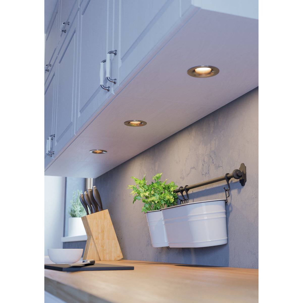 Kamarne LED Downlight set of 3 in satin nickel, round recessed fittings fitted under white kitchen cabinetry, illuminating a worktop with plants and a knife block.