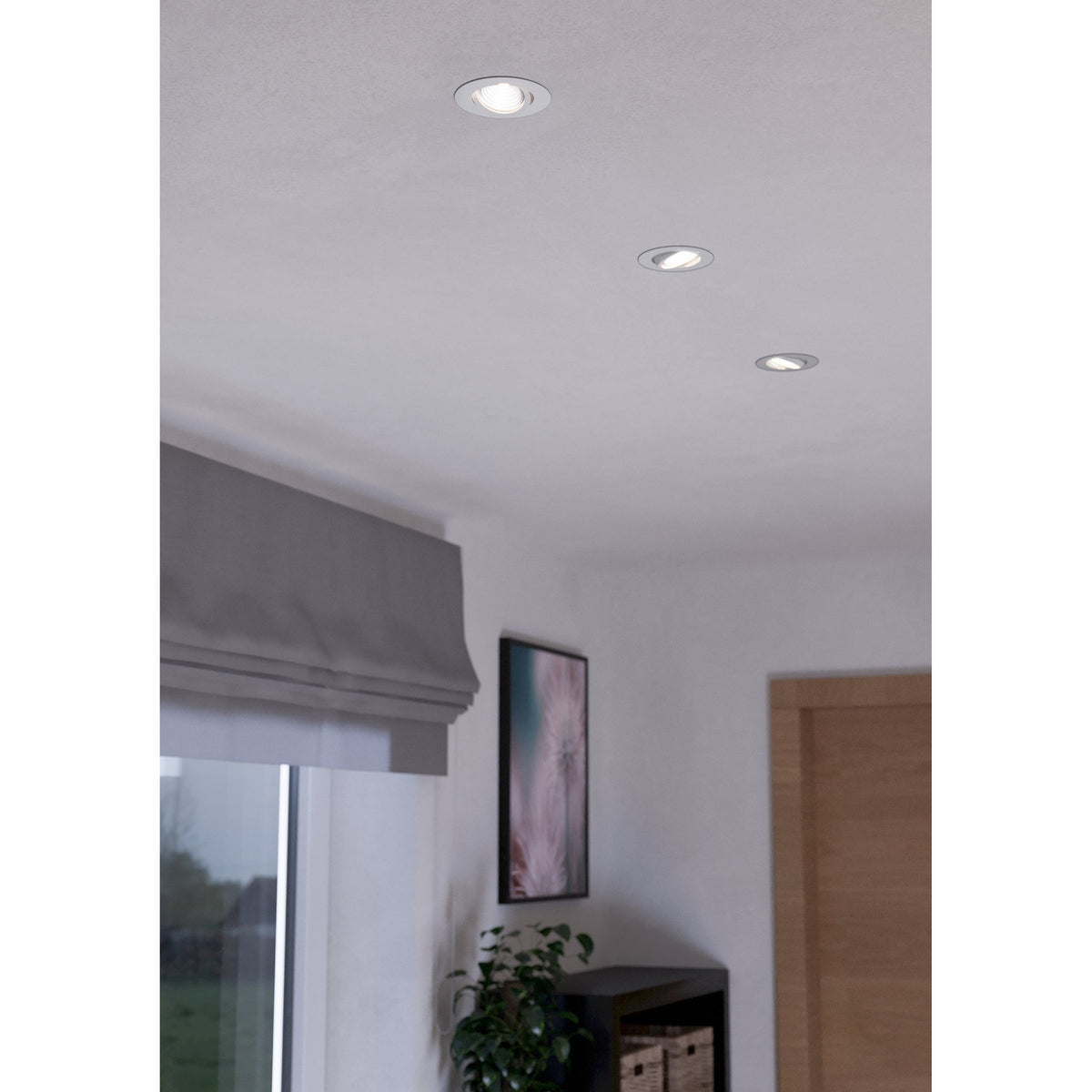 Kamarne LED Downlight set of three round white aluminium fittings with tilting silver reflector rings, recessed into a white ceiling above a window and sideboard.