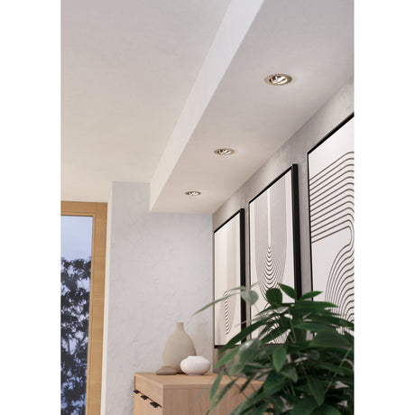 Kamarne LED Downlights, set of three round satin nickel fixtures with tiltable heads, recessed into a hallway ceiling above framed wall art and a wooden console.