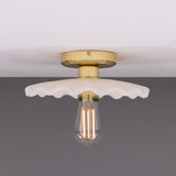 Kapok ceramic ceiling light with a wide scalloped matt white striped shade, brass lampholder and round ceiling plate, shown with an exposed bulb against a plain background.