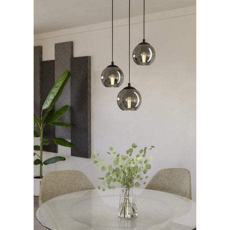 Karnarne 3 Light Pendant in black with round smoked glass globes at staggered heights, shown above a glass dining table in a living space.