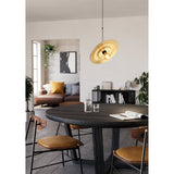 Karnette Pendant Light with black cord and canopy, featuring a wide, shallow brushed brass disc shade, hung above a round dark wood dining table.
