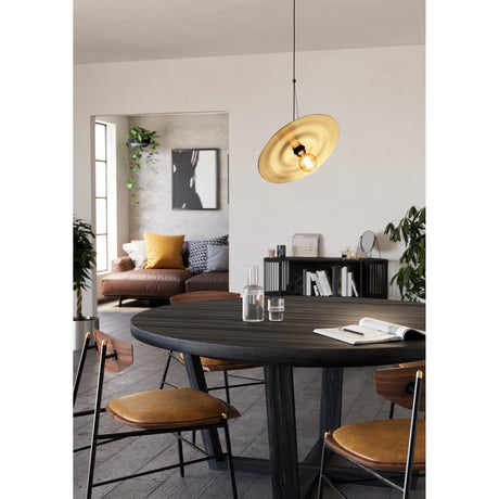 Karnette Pendant Light with black cord and canopy, featuring a wide, shallow brushed brass disc shade, hung above a round dark wood dining table.