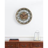 Kenema 46cm round wall clock with skeleton face, cut-out Arabic numerals, exposed antique gold gears and metal frame, shown above a wooden sideboard with candle lantern and books.