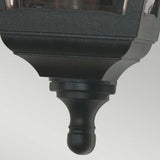 Close-up of the Kerry 1 Light Outdoor Flush Wall Light in black, designed to be corrosion-proof and boasting an IP44 rating. It showcases a decorative finial and modern, minimalist design with a rectangular shape and slightly reflective surfaces, set against a light gray background.