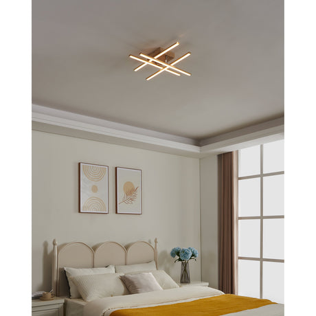 Keselle LED flush ceiling light with four overlapping slim bars in a light brown wood-effect finish, mounted on a bedroom ceiling above a bed and framed artwork.