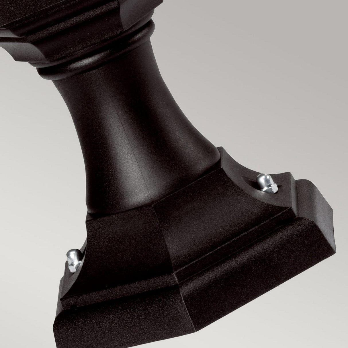 Close-up of the Kinsale 1 Light Pedestal/Porch Light - Black against a light gray background. The weather-resistant stand showcases a square base with beveled edges and two visible screws securing a curved central column, ideal for outdoor lighting setups.