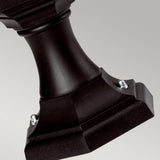 Close-up of the Kinsale 1 Light Pedestal/Porch Light - Black against a light gray background. The weather-resistant stand showcases a square base with beveled edges and two visible screws securing a curved central column, ideal for outdoor lighting setups.