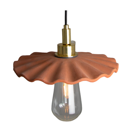 Kirhii ceramic pendant light in Red Iron glaze with a wavy-edged shade, brass fittings, and exposed bulb in a glass cover, shown on a plain white background.