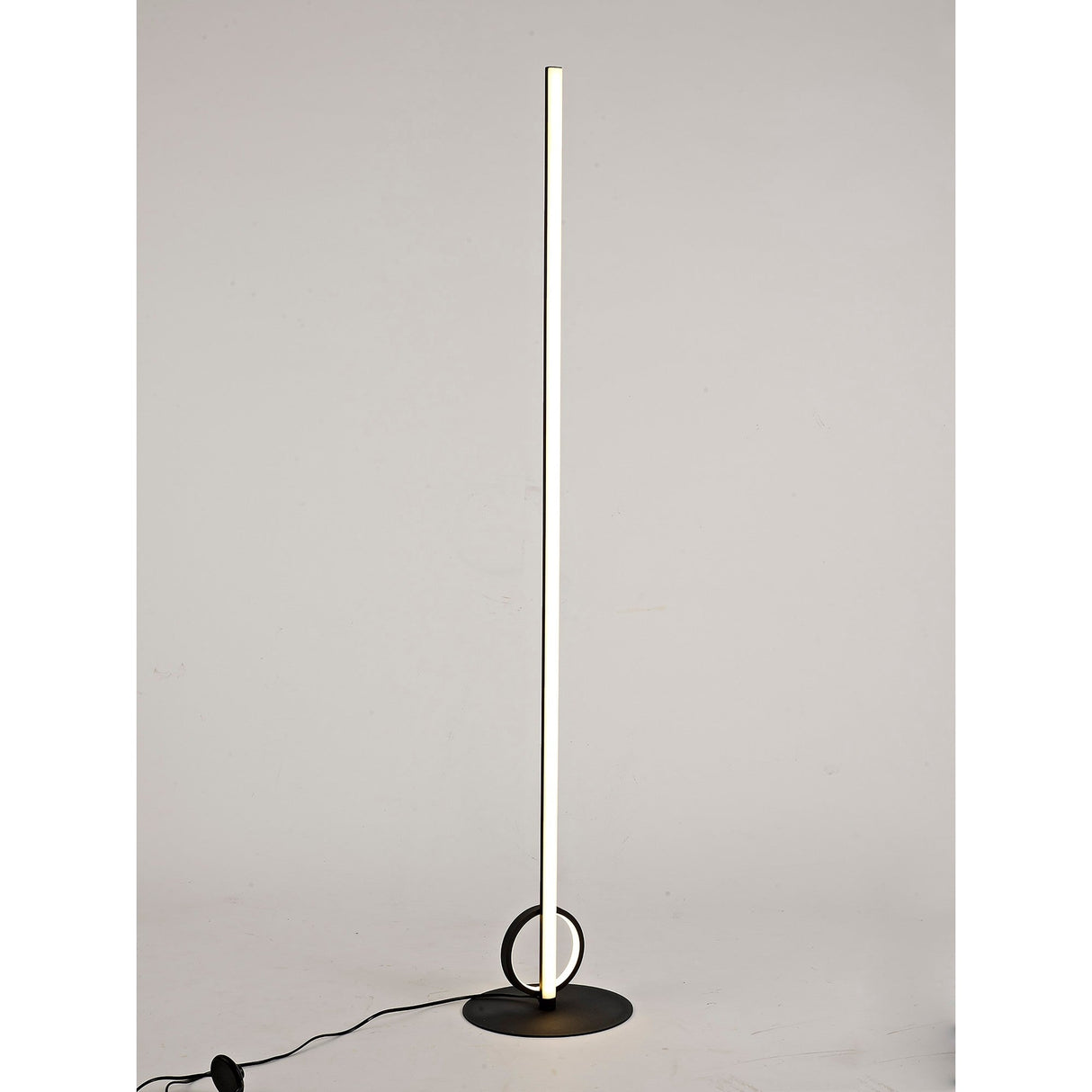 The Kitesurf LED Floor Lamp 24W 3000K in black features a slim vertical light bar and round base with a circular accent—a minimalistic touch ideal for modern lighting enthusiasts.