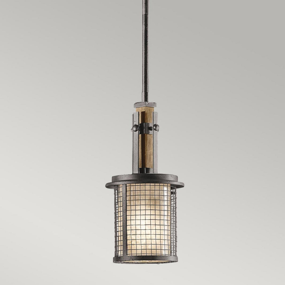 The Ahrendale 1 Light Mini Pendant in Grey showcases an industrial style with its cylindrical design. It includes a mesh metal casing and is suspended from a single rod, allowing the warm glow to diffuse through its frosted inner shade, capturing the essence of industrial-inspired lighting.