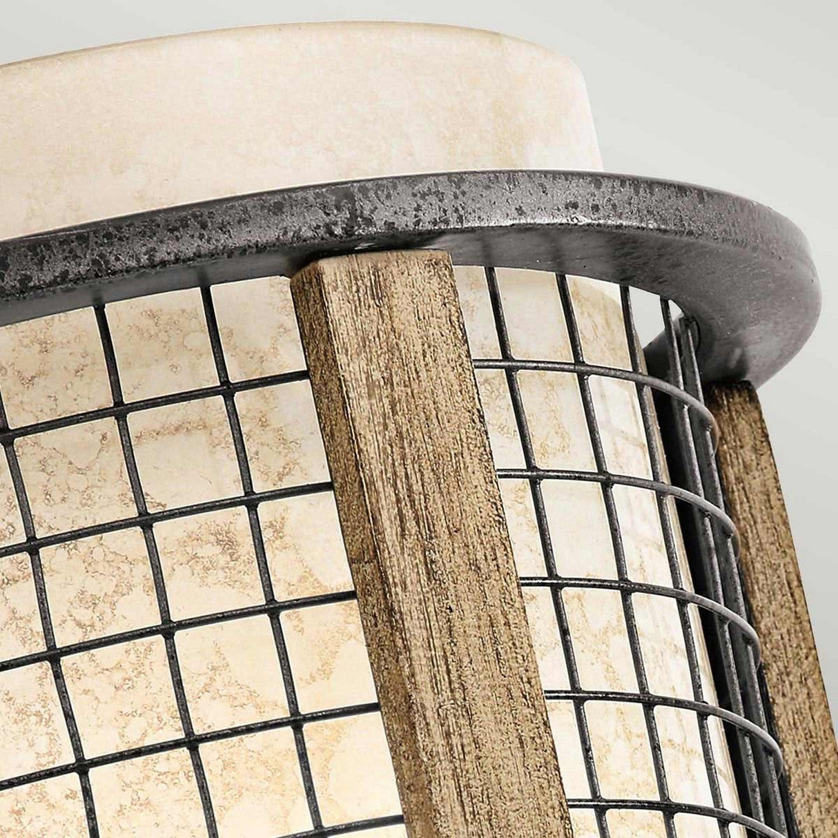 Detailed view of the Ahrendale 1 Light Wall Light in grey, featuring a stone-textured cylindrical surface encased in Anvil Iron mesh. Wooden supports enhance the sides, providing a charming accent to the modern Vetro Mica shade design.