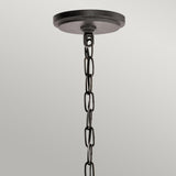 The Ahrendale 4 Light Chandelier in Grey exudes rustic charm with its black metal ceiling canopy and a chain composed of repeated oval links, creating an industrial look reminiscent of Anvil Iron mesh against a plain gray background.