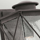 Close-up of the Argyle Outdoor 1 Light Medium Wall Light, showcasing its vintage style with a weathered zinc metal frame and textured seeded glass panels reminiscent of raindrops. Mounted on a wall, this lantern exudes rustic elegance and classic charm.