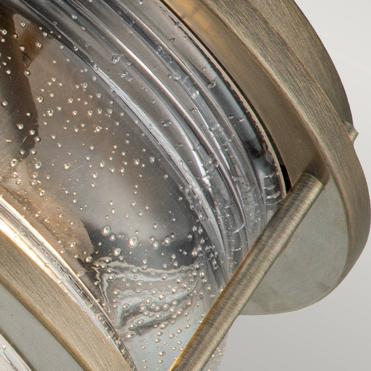 Close-up of the Ashland Bay Outdoor 2 Light Outdoor Ceiling Flush, showcasing a clear glass fixture with bubble-like textures, framed in burnished bronze. The glass design creates an artistic pattern with reflections, and Edison-style bulbs add a modern touch to the fixture.